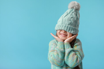 Stylish little girl in winter clothes on color background