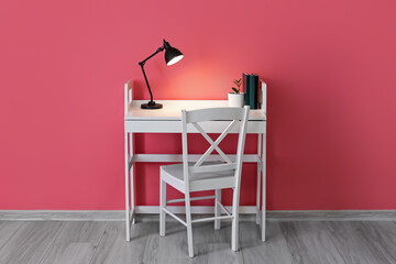 Fototapeta na wymiar Modern workplace with glowing lamp near color wall in room