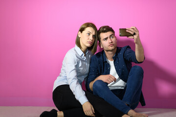 a happy young couple sitting on the floor in the house and making selfie