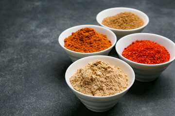Bowls with different spices on dark background
