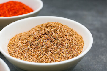 Bowl with pepper powder on dark background, closeup