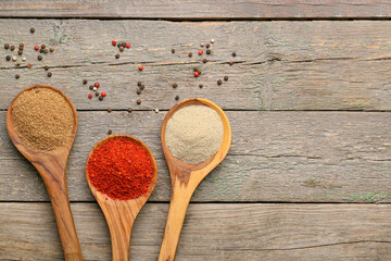 Spoons with different spices on wooden background