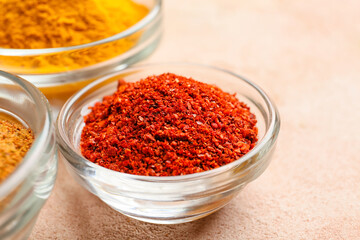 Bowls with red pepper powder on color background, closeup