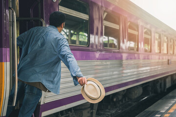 A man with hat holding handrail in train at the open door. People travel local transport.
