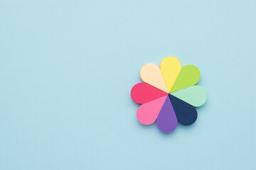 A flower made of cosmetic multi-colored sponges on a blue background.