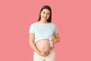 Young pregnant woman with toy on color background