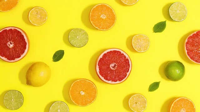 Creative dancing moving pattern made of citrus fruits and leaves on summer yellow background. Stop motion flat lay