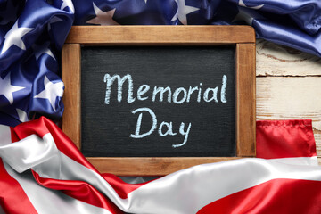 Fototapeta na wymiar Chalkboard with text MEMORIAL DAY and USA flag on table