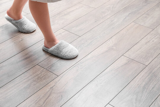 Woman In Slippers Walking On New Laminate Flooring At Home