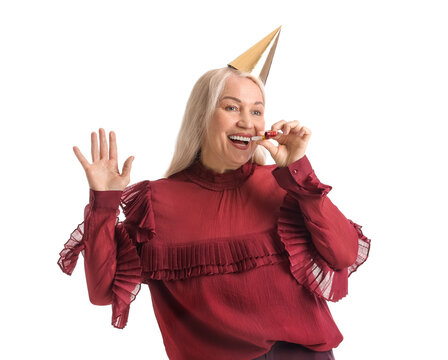 Mature woman in party hat and with noisemaker on white background