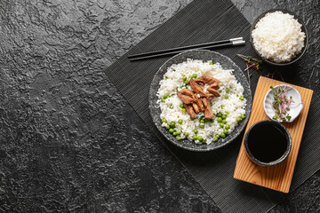 Plate with tasty rice, green peas and meat on dark background