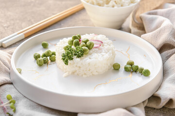 Plate with tasty rice, green peas and radish on grunge background, closeup
