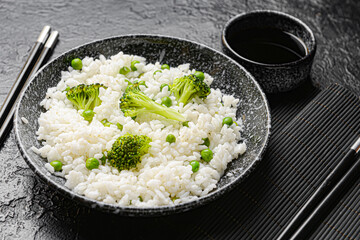 Plate with tasty rice and broccoli on dark background