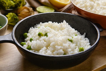 Frying pan with tasty rice on wooden background