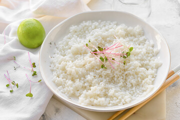 Plate with tasty rice on light background