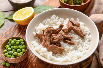 Plate with tasty rice and meat on wooden background