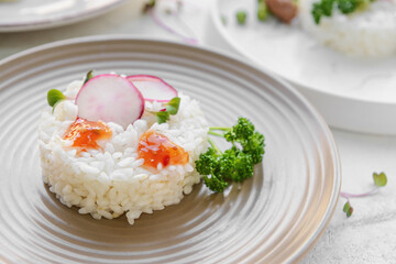 Plate with tasty rice and radish on light background