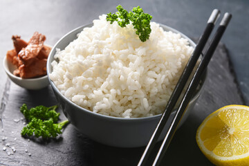Bowl with tasty rice and meat on dark background