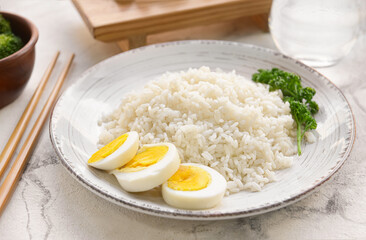 Plate with tasty rice and boiled egg on light background