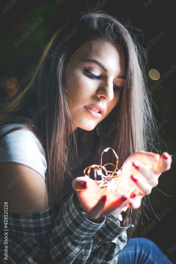 Sticker Vertical shot of a charming Caucasian woman with a light decoration on her hands