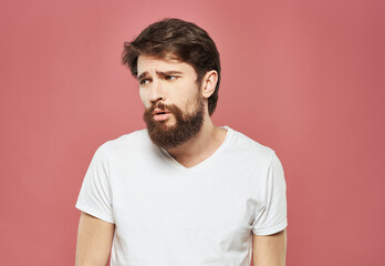 Obraz premium Man with a brunet beard pink background white t-shirt emotions