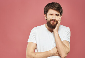 Obraz premium Guy touches his face with his hands on a pink background cropped view