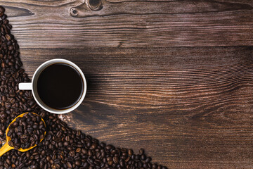 Black coffee in white cup and roasted coffee bean on wooden backdrop.