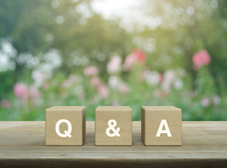 Q and A letter on block cubes on wooden table over blur pink flower and tree in garden, Frequently...