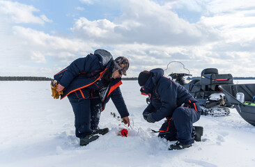 Fototapeta na wymiar fisherman fishing on frozen lake. snowmobiling, winter sports