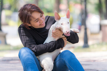 An Asian woman is holding a bull terrier.  Young woman hug bull terriear dog.