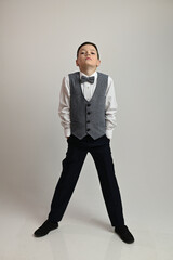 Portrait of a boy in a suit with a bow tie on a white background in full growth