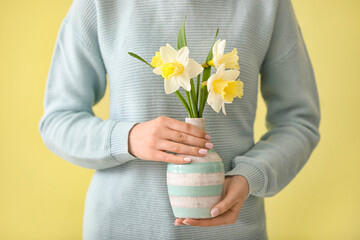 Woman with beautiful daffodils on color background