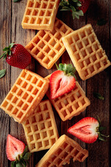 Waffles with strawberries on an old wooden table.
