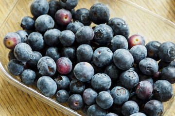 Purple large blueberries in a transparent bowl.