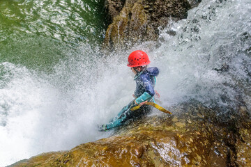 Mutprobe beim Canyoning - kleiner Junge in einer Felsrutsche im Wasserfall
