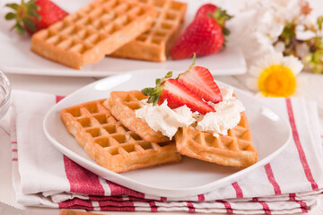 Waffles with strawberries and whipped cream.