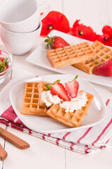 Waffles with strawberries and whipped cream.