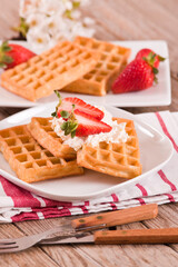Waffles with strawberries and whipped cream.