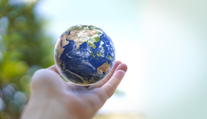 Human hand holds small Earth with care and love. Planet Earth globe ball in human hand. Strong Human  hands support planet. Earth day and saving planet. Environment conservation concept. 
