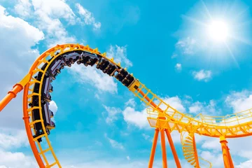 Fotobehang Amusementspark achtbaan hoog in de zomerhemel in themapark meest opgewonden leuke en vrolijke speelmachine