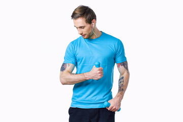 Fototapeta premium guy with dumbbells go in for sports in a blue t-shirt on a light background