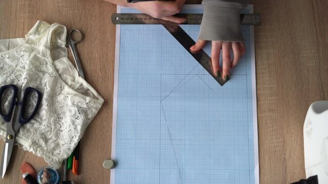 Top view of female hands are drawing design of a new collection of lingerie. Workplace of a professional designer.