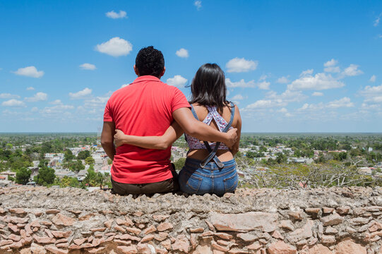 Espalda de pareja de enamorados abrazados contemplando la ciudad desde una colina. Tekax, Yucatán