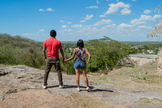 Pareja de enamorados tomados de la mano contemplando la naturaleza desde un acantilado. Tekax, Yucatán