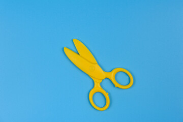 Yellow baby scissors on a blue background. Close-up.