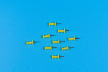 Nine push pins pointing one way on a blue background