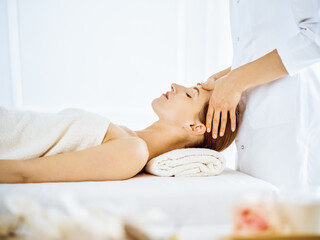 Obraz na płótnie Canvas Beautiful woman enjoying facial massage with closed eyes in spa center