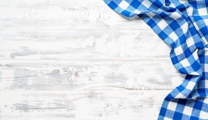 White wooden table covered with blue tablecloth. View from top. Empty tablecloth for product...