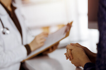 Doctor and patient discussing current health examination while sitting in sunny clinic. Perfect medical service in hospital
