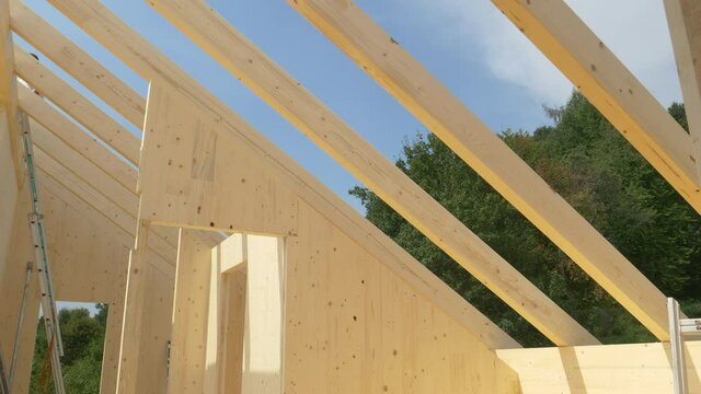 Uncovered roof of a modern cross laminated timber house under construction reveals the clear blue springtime sky. Beautiful shot of the interior of contemporary glued-laminated wood house in progress.